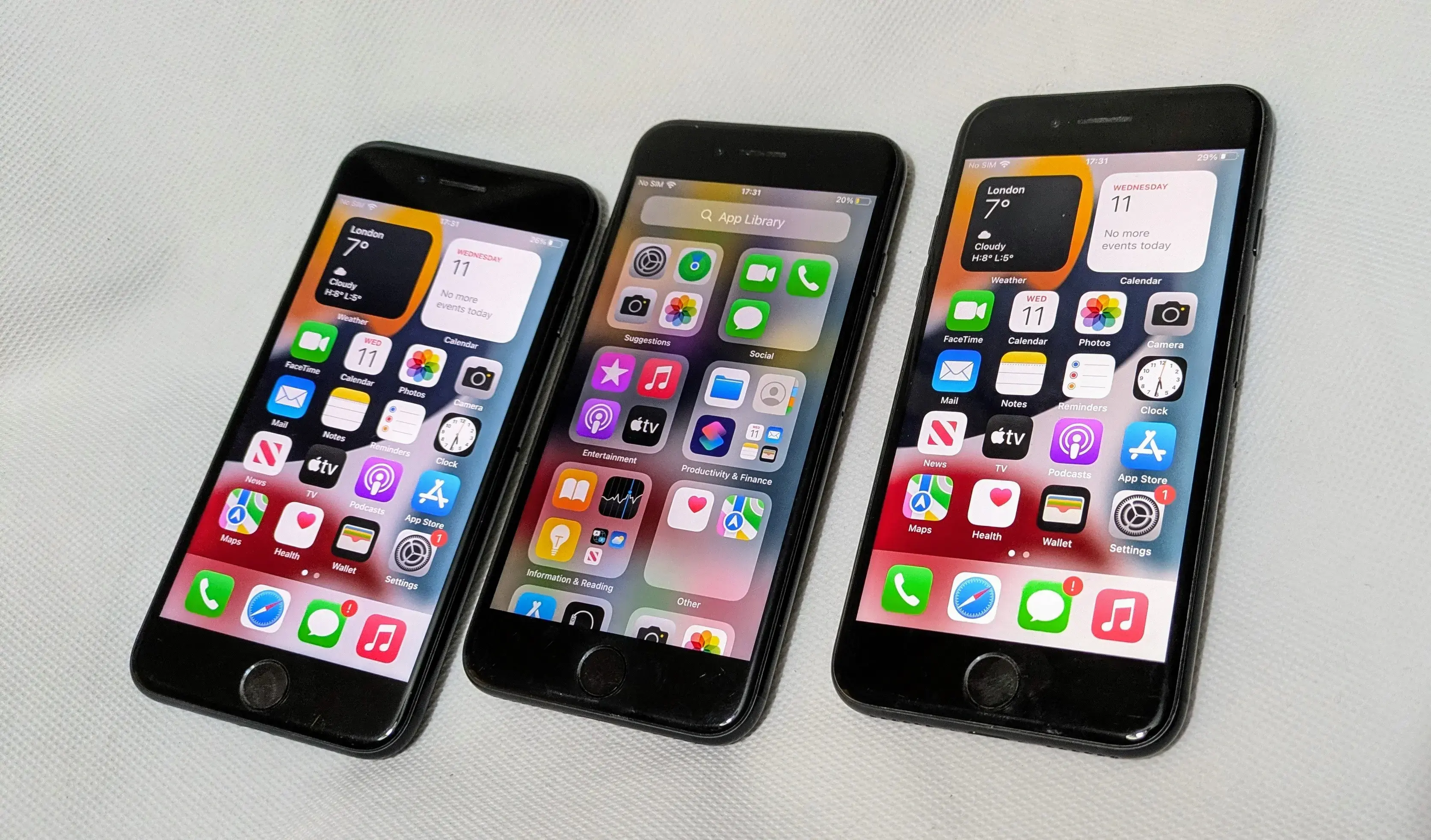 Three unlocked iPhone 7 devices displayed side by side, showcasing their home screens with various app icons and widgets.