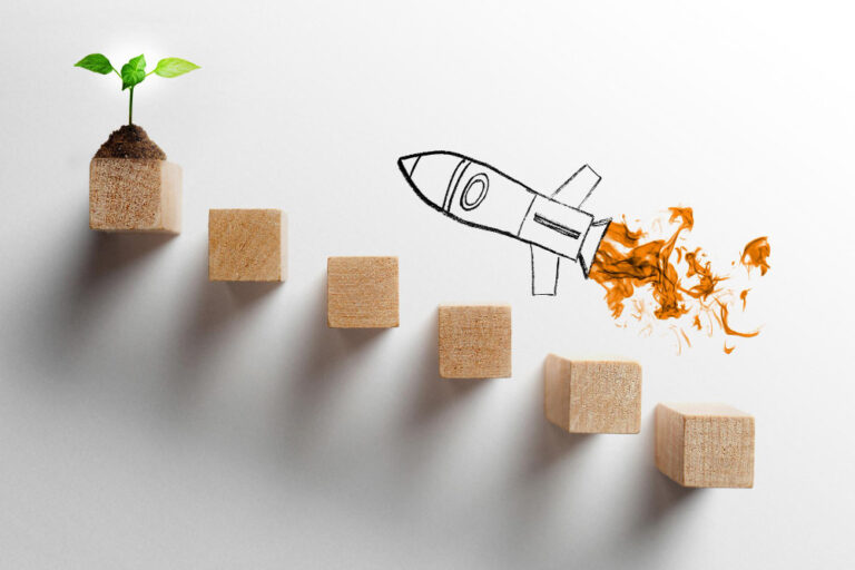 growth Wooden blocks arranged as steps with a small plant sprout and a hand‑drawn rocket symbolising growth and progress.