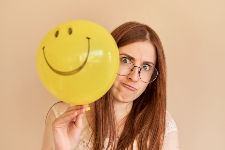 Woman smiling and holding a yellow balloon to represent emotional intelligence and personal growth